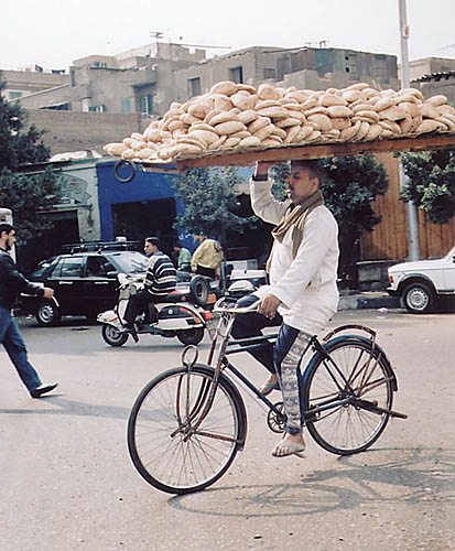 man carries bread on bike - photograph